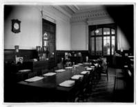 [Biblioteca Nacional 1927. Salones interiores, con una mesa rectangular y varias personas]
