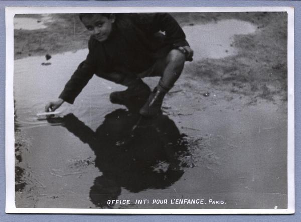 [Niño refugiado en el campo de concentración de Chartres, jugando en una poza de agua]