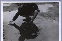 [Niño refugiado en el campo de concentración de Chartres, jugando en una poza de agua]