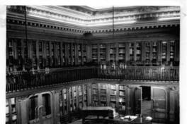 [Biblioteca Nacional. Sala de lectura de la Biblioteca Americana de Diego Barros Arana, se divisan unos escritorios y una mesa rectangular con libros]